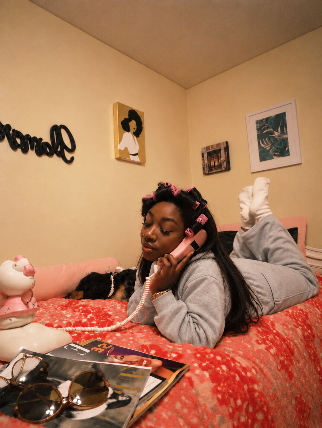 Woman in a gray set talking on a pink telephone at home